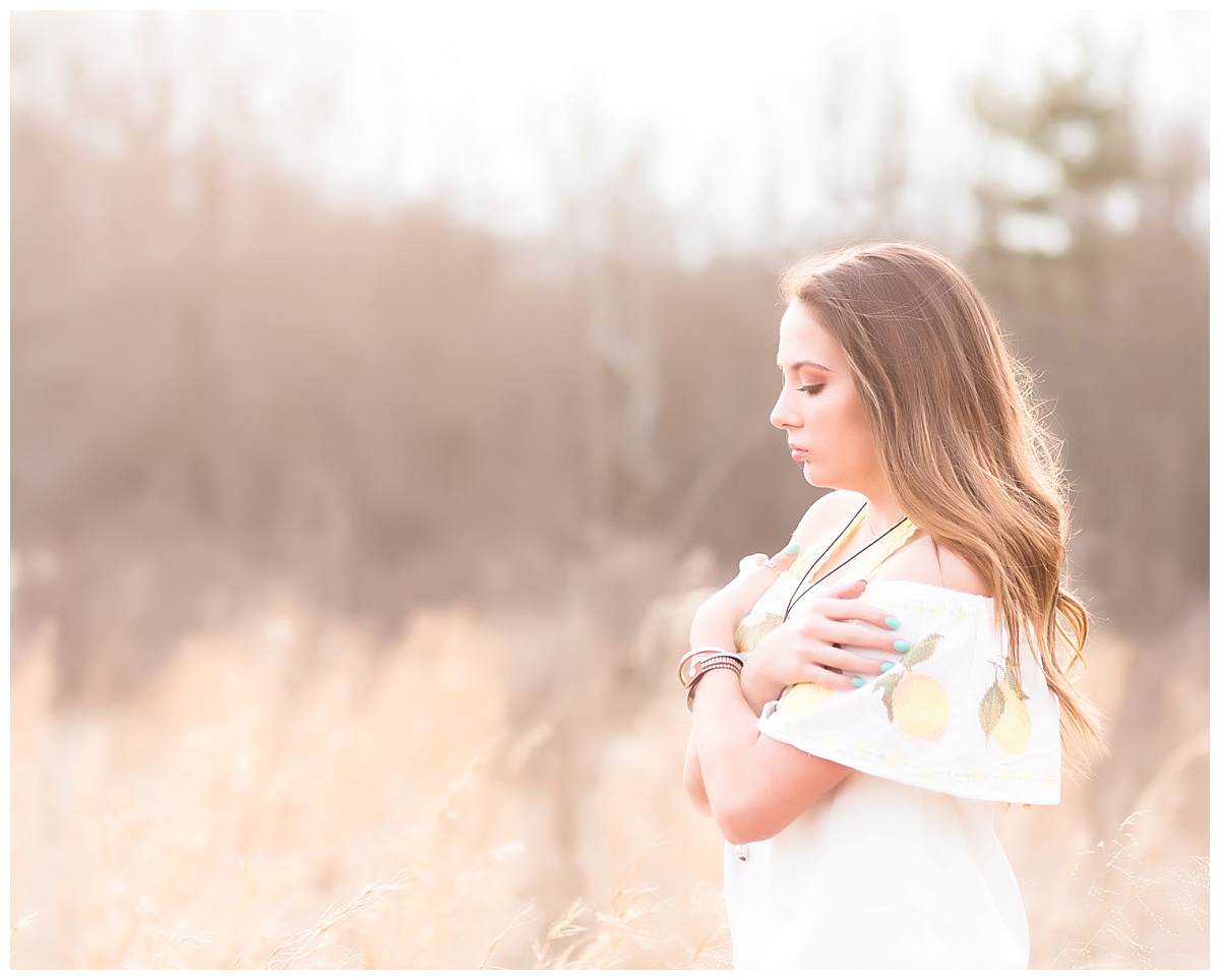 senior girl-- looking off into the distance standing in field of grass-