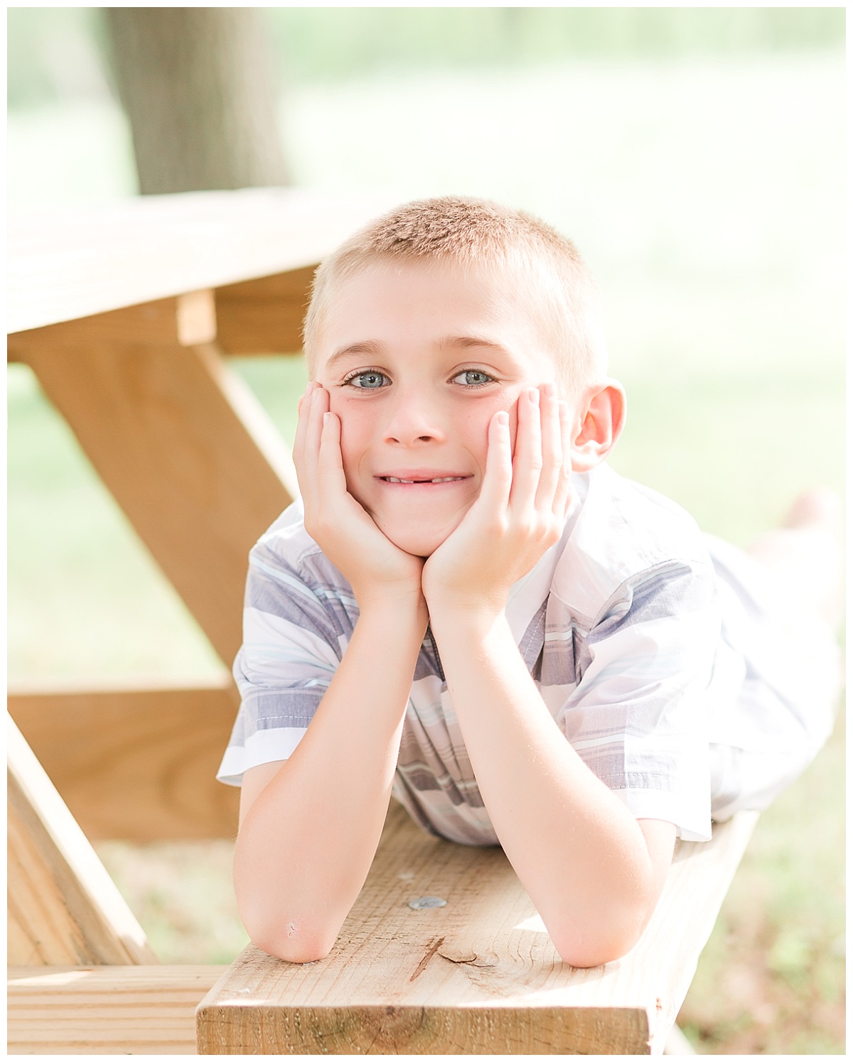 young boy laying on picnic bench