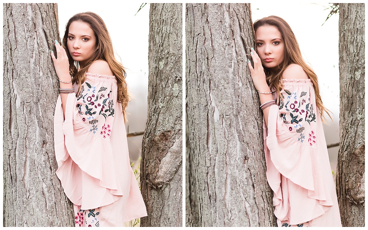 Senior girl in pink dress standing by a tree