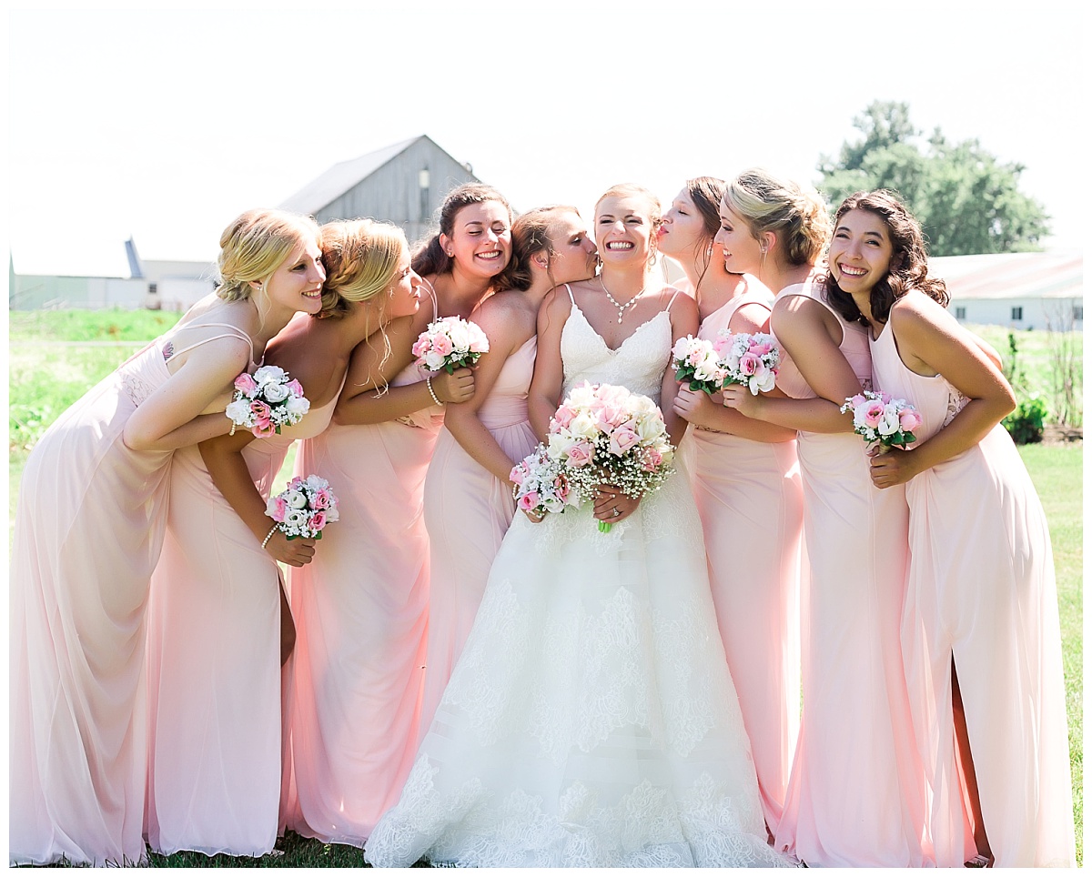 bridesmaids in pink dresses laughing and smiling with bride