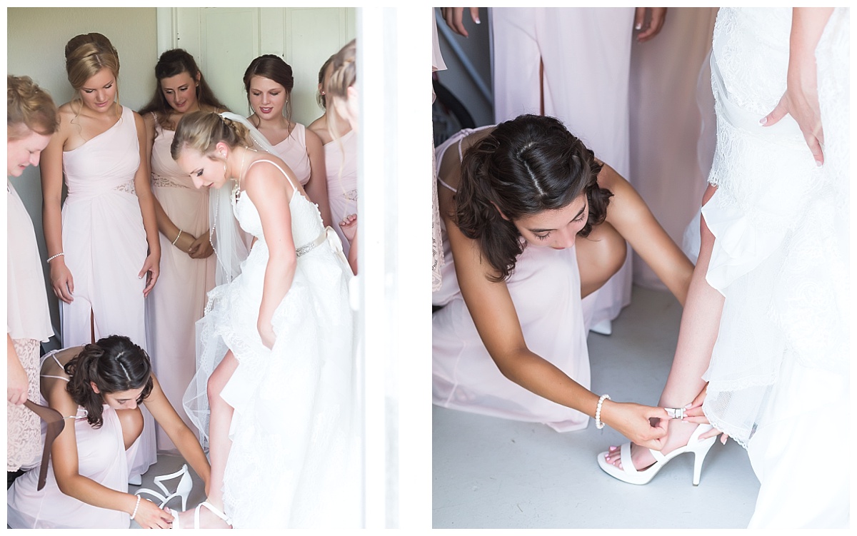 bridesmaids in pink dresses helping bride put on shoes