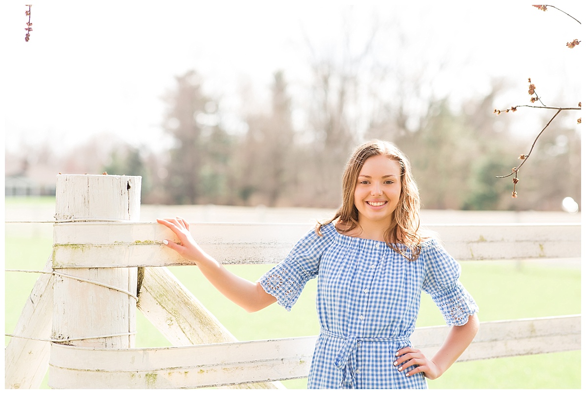 senior girl in front of white fence